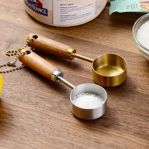 Premium 14ml gold and silver measuring spoons with wooden handles on a cutting board
