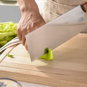 Green elephant-shaped manual knife sharpener on wooden cutting board in kitchen setting