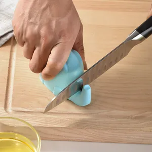 Blue elephant manual knife sharpener being used on a wooden cutting board in a kitchen.