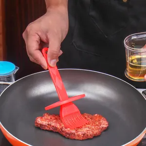 Red silicone basting brush for BBQ and kitchen cooking in frying pan