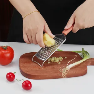 Grattugia manuale in acciaio inossidabile per grattugiare lo zenzero su un tagliere