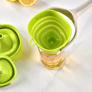Bright green foldable silicone funnel with handle set on a glass for kitchen oil