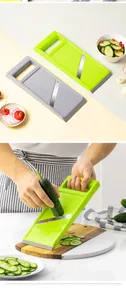 Handmatige mandolinesnijder in groen en grijs met demonstratie van komkommer snijden
