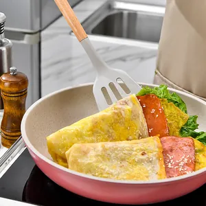 Heat-resistant silicone spatula with wooden handle flipping omelets in a non-stick frying pan