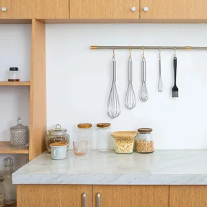 Ensemble professionnel de quatre fouets en inox et un pinceau en silicone suspendus en cuisine