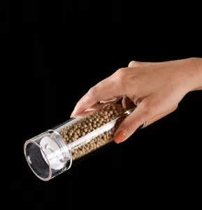 Ergonomic clear acrylic pepper grinder with oak lid showing comfortable grip and use