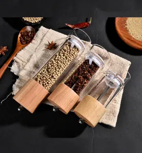 Close-up detail of manual oak wood and clear acrylic pepper grinders with fresh spices