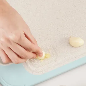 Double-sided kitchen cutting board with integrated garlic grater feature for mincing