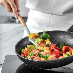Action shot of light green silicone spatula with wooden handle in a frying pan