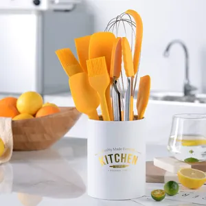 Yellow silicone kitchen utensil set with white storage holder tube in kitchen.