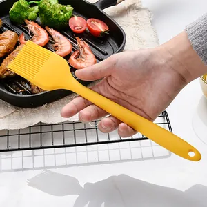 Large yellow heat-resistant silicone basting brush for BBQ and baking held over food