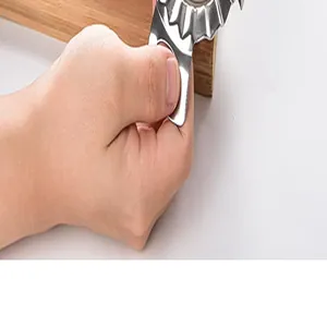 Macro view of a handheld stainless steel pastry wheel cutter on a wooden board.