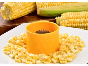 Yellow circular corn stripper tool shown with fresh corn kernels on a white ceramic plate