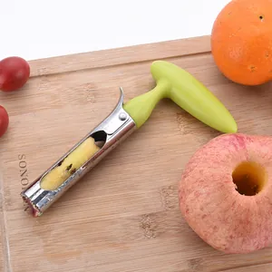 Stainless steel apple corer tool with green handle for fruit core removal on a wooden board