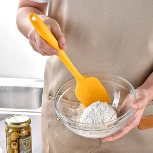 Ergonomic yellow silicone spatula tool used for mixing flour in a professional kitchen