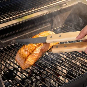 Premium stainless steel BBQ tongs with wooden handles flipping salmon on a grill
