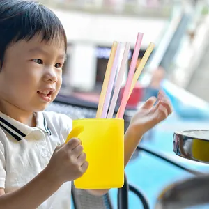 Reusable food-grade colorful silicone straws held by a child in an outdoor setting