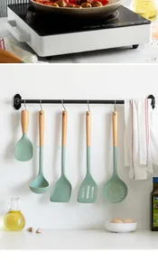 Detailed view of five-piece green silicone kitchen utensils with wooden handles on a rack