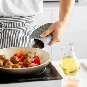 Gray honeycomb silicone heat insulation mat used to hold a hot frying pan handle