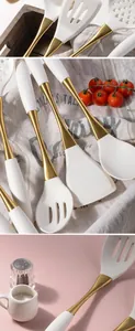 Detail van wit siliconen keukengerei met elegante gouden roestvrijstalen handgrepen.