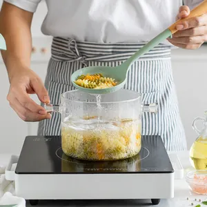 Ergonomic green silicone soup ladle with wooden handle used for cooking pasta in kitchen