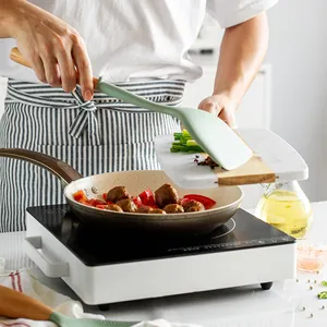 Silicone cooking turner with long wooden handle for non-stick pans in kitchen scene.