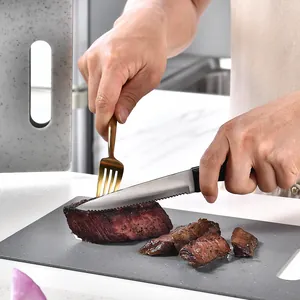 Durable grey PP plastic cutting board being used to slice cooked steak in a kitchen