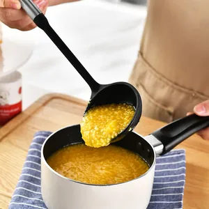 Silicone soup ladle with stainless steel handle scooping hot porridge from a small pan
