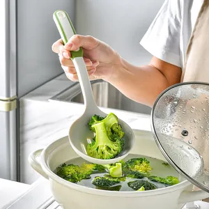 Heat-resistant silicone slotted spoon strainer lifting fresh broccoli from a white pot