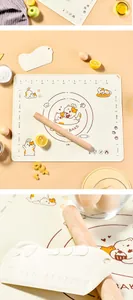 Close-up of cream silicone kneading mat with orange cat print and natural wooden rolling pin.