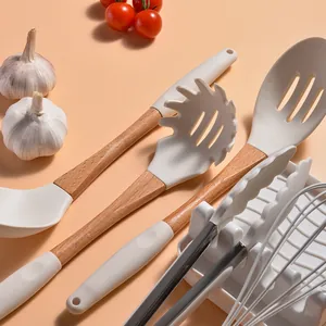 Crèmekleurige siliconen keukengerei set met houten handgrepen op een perzikkleurige basis