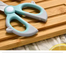Close-up of mint green ergonomic handles on stainless steel children's food scissors