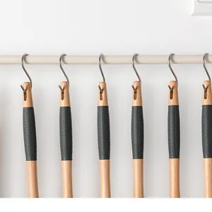 Detail view of stainless steel S-shaped hooks hanging wooden handle kitchen utensils