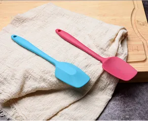 Detailed view of pink and blue food-grade silicone spatulas on a linen cloth and wooden board