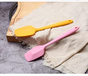 Food-grade silicone cake spatulas in yellow and pink displayed on a rustic wooden board