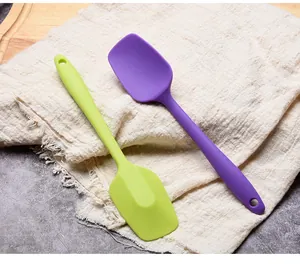 Close-up detail of purple and green food-grade silicone spatulas on rustic linen cloth