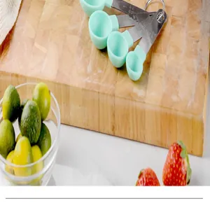 Detail view of mint green measuring spoons with stainless steel handles on wooden board