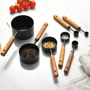 8-piece matte black stainless steel measuring set with wooden handles on marble surface