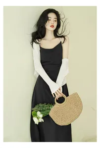Elegant French style black slip dress with white knit bolero and straw bag accessories.