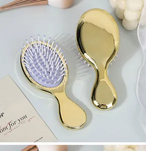 Close-up of golden mini cushion hairbrushes with lavender soft massage bristles.