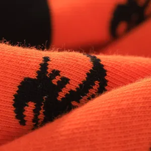 Makroansicht orangefarbener Halloween-Socken mit gestricktem Vogelscheuchen-Muster-Textur