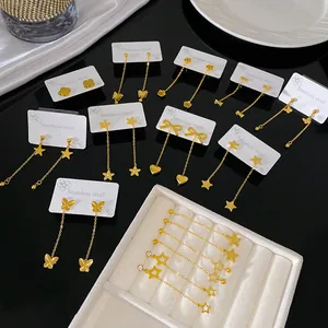 Detailed view of gold-toned stainless steel earrings with butterfly and star motifs