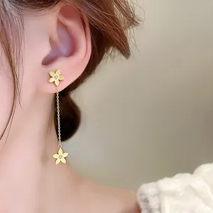 Detailed macro view of elegant gold flower tassel earrings worn on ear
