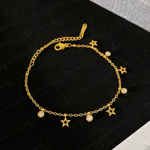 Close-up of gold star and round zircon charms on a delicate link chain bracelet.