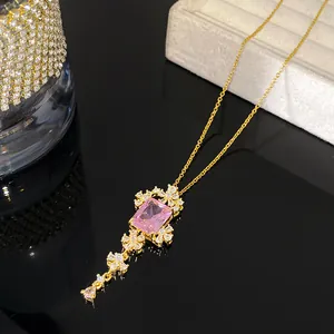 Detailweergave van gouden ketting met rechthoekige roze edelsteen en bloemenaccenten