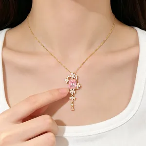 Gedetailleerd overzicht van gouden ketting met roze edelsteen gedragen door een model.