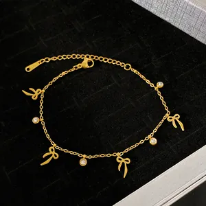 Detailed view of gold bow charm bracelet with crystals on black background