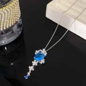 Detailweergave van een florale zilveren ketting met een rechthoekige blauwe hanger.