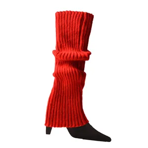 Vibrant red ribbed knitted leg warmers shown in detail over black pointed heels