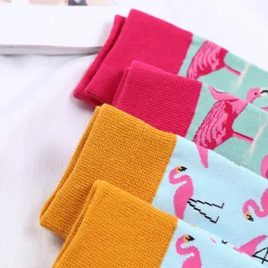 Gros plan détaillé des motifs flamants roses colorés sur des chaussettes en coton tricoté.